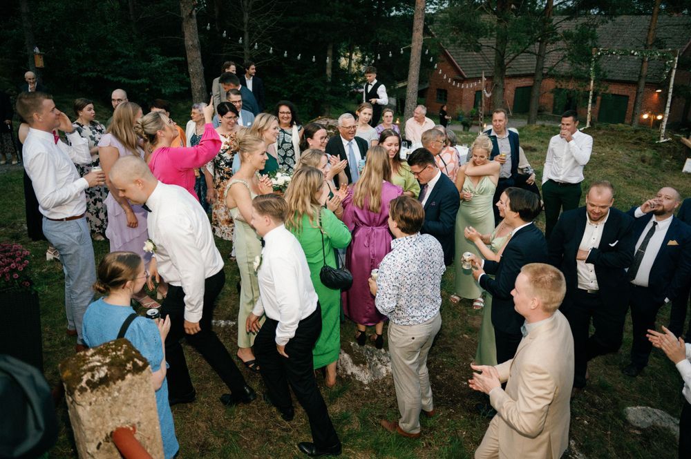 Festive crowd celebrates at an outdoor wedding reception.
