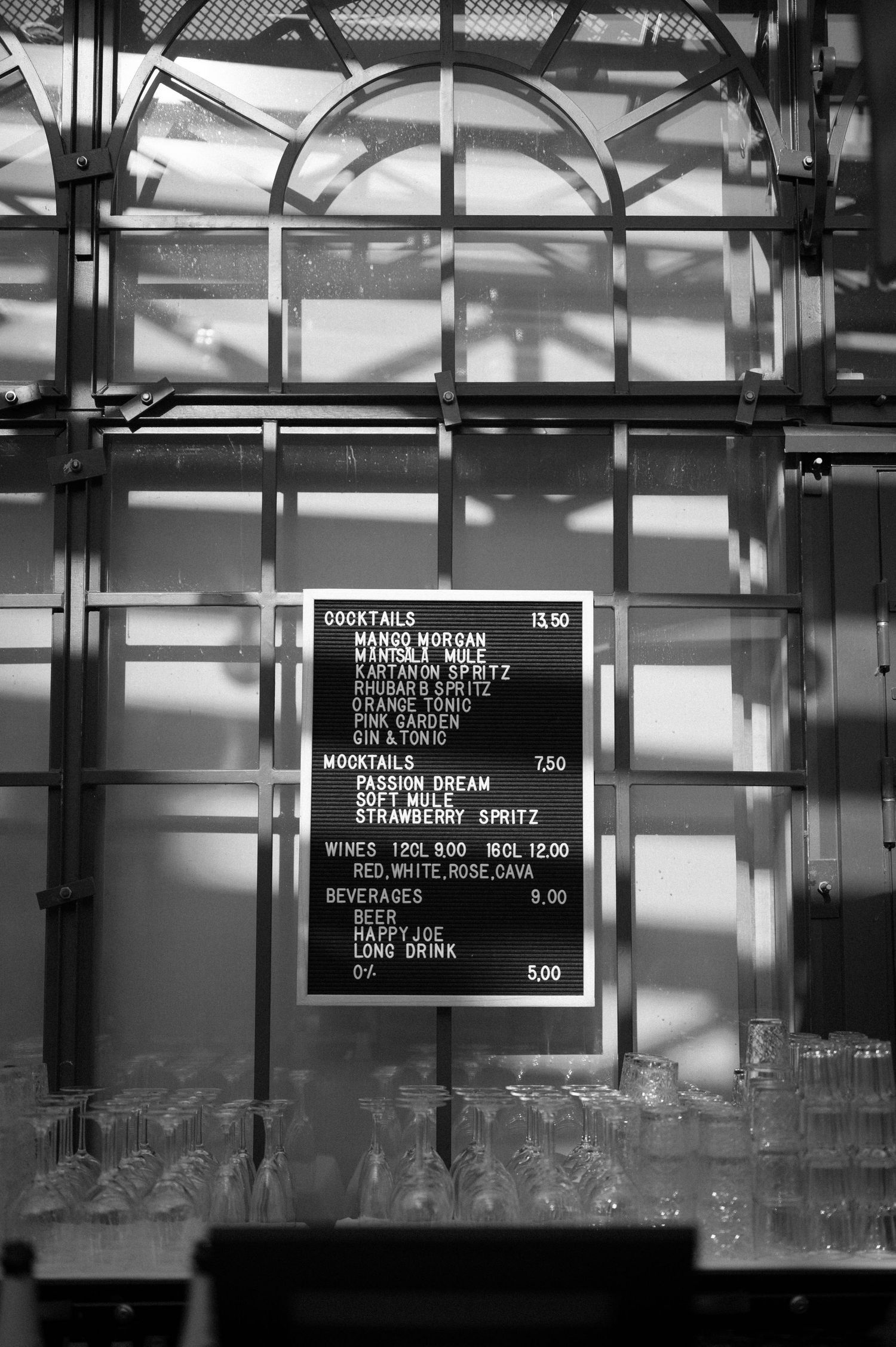 Menu board displaying cocktail prices and drink options in black and white.