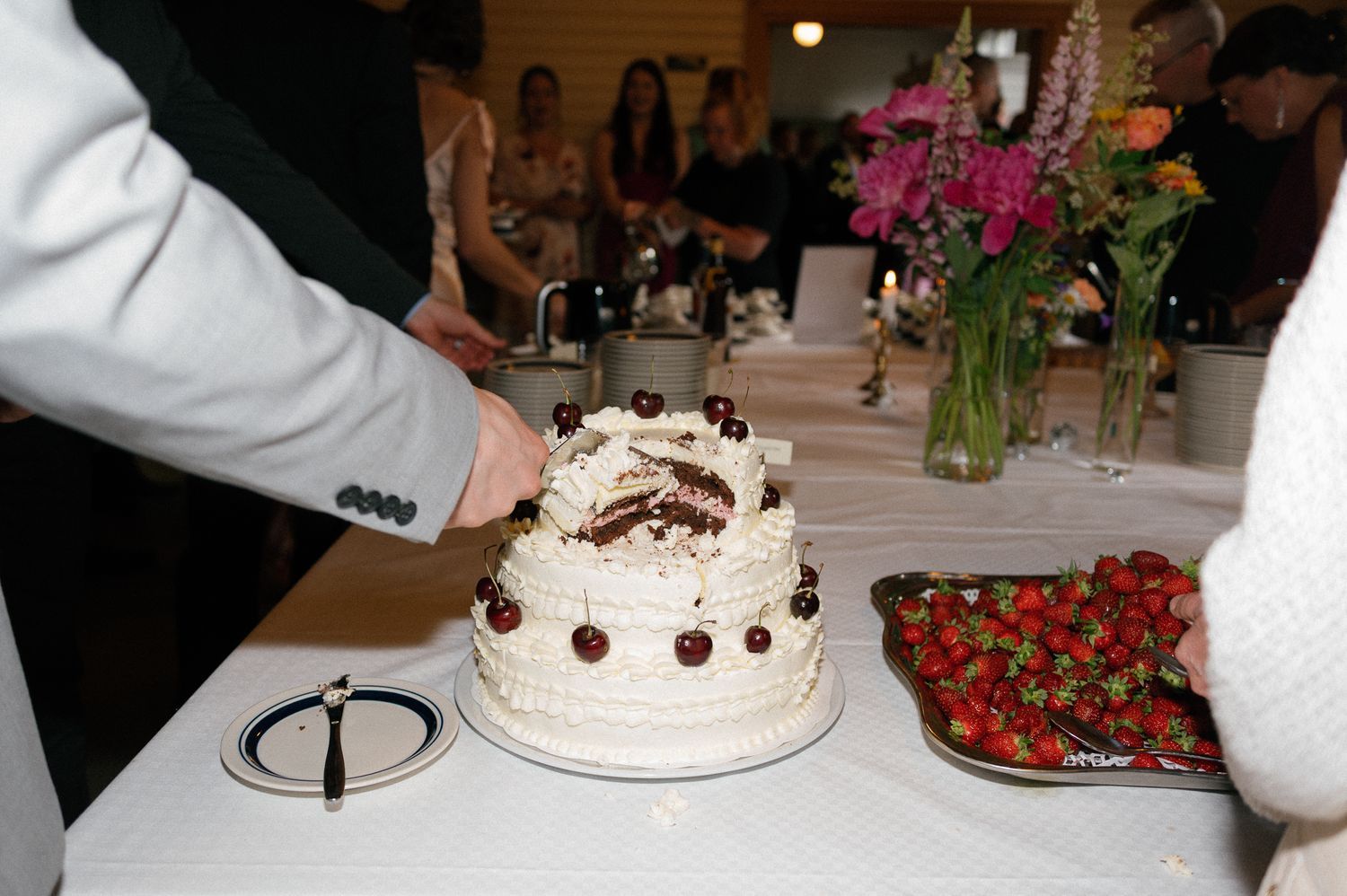 Wedding reception dessert table with white cake and fresh strawberries.