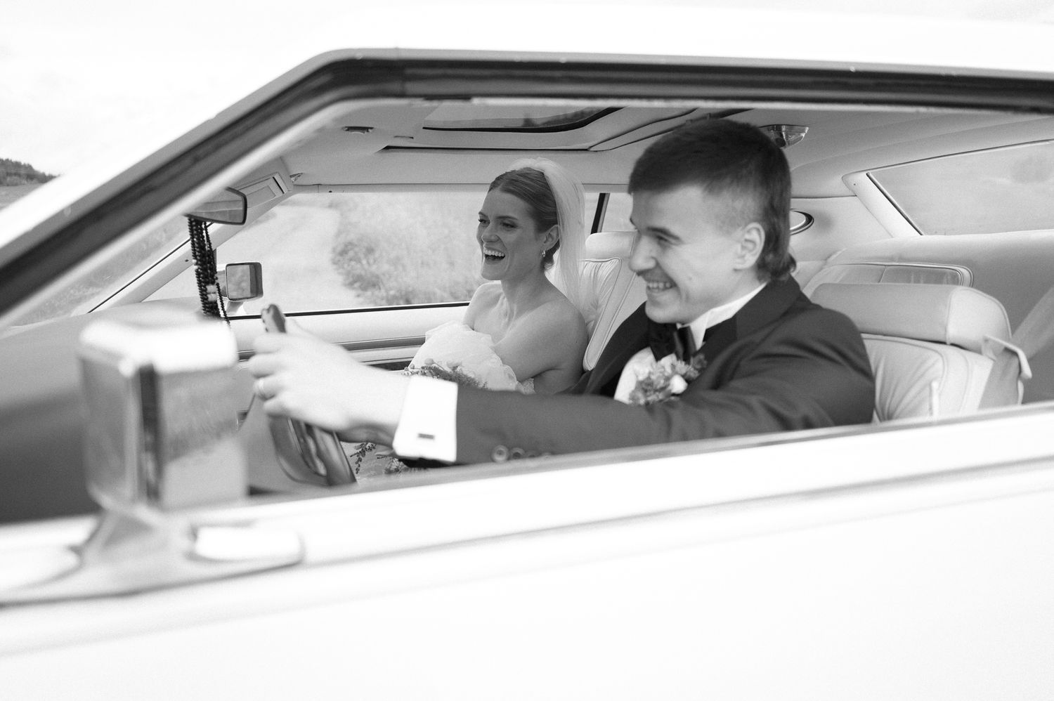 Side view through car windows showing elegant wedding day transportation.