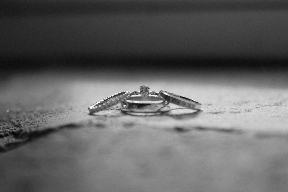 Wedding rings photographed in dramatic black and white lighting.