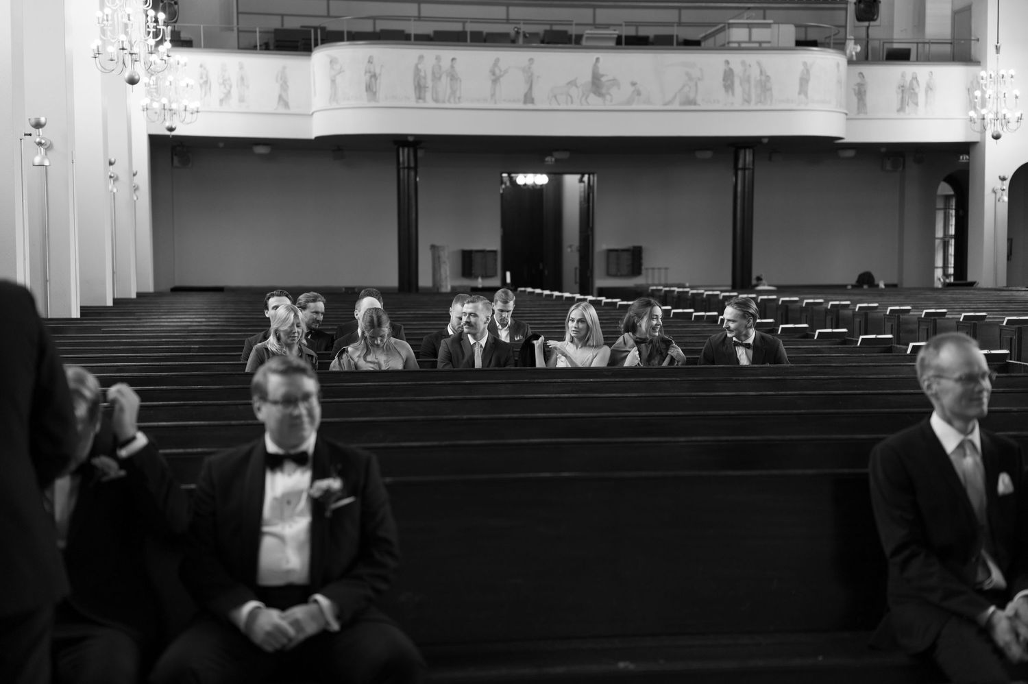 Black and white photograph showing people seated sparsely in rows of pews inside a church or auditorium.