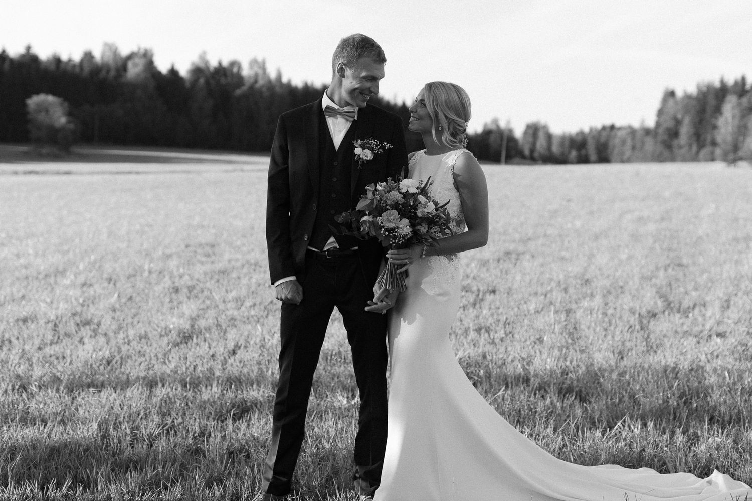 Black and white portrait of couple sharing intimate moment in countryside setting.