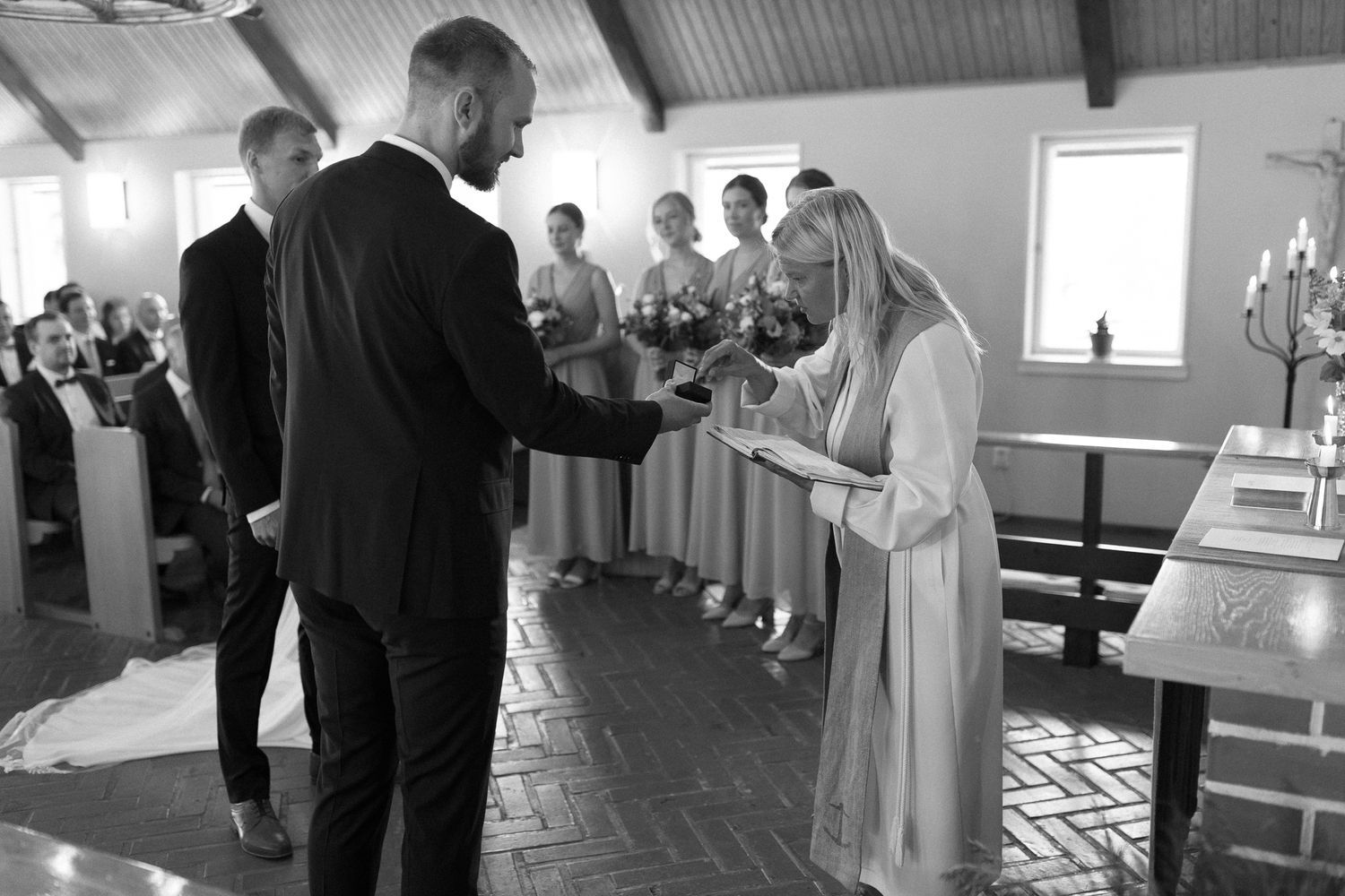 Black and white photo of a wedding ceremony exchange taking place in a church.