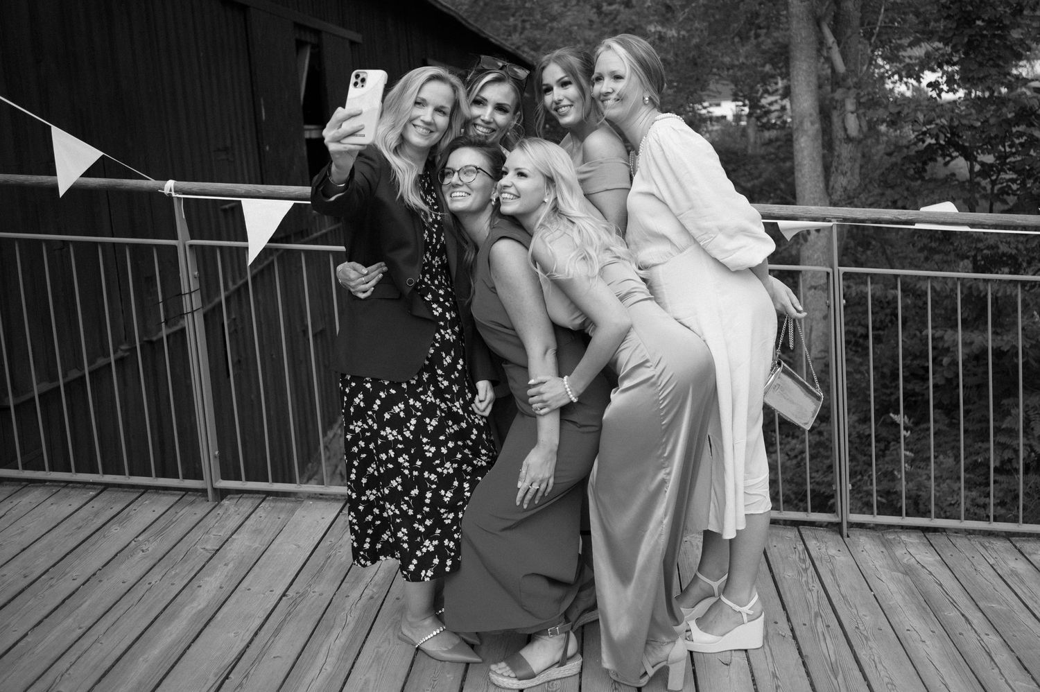 A group poses playfully together on a wooden deck with bunting decorations.