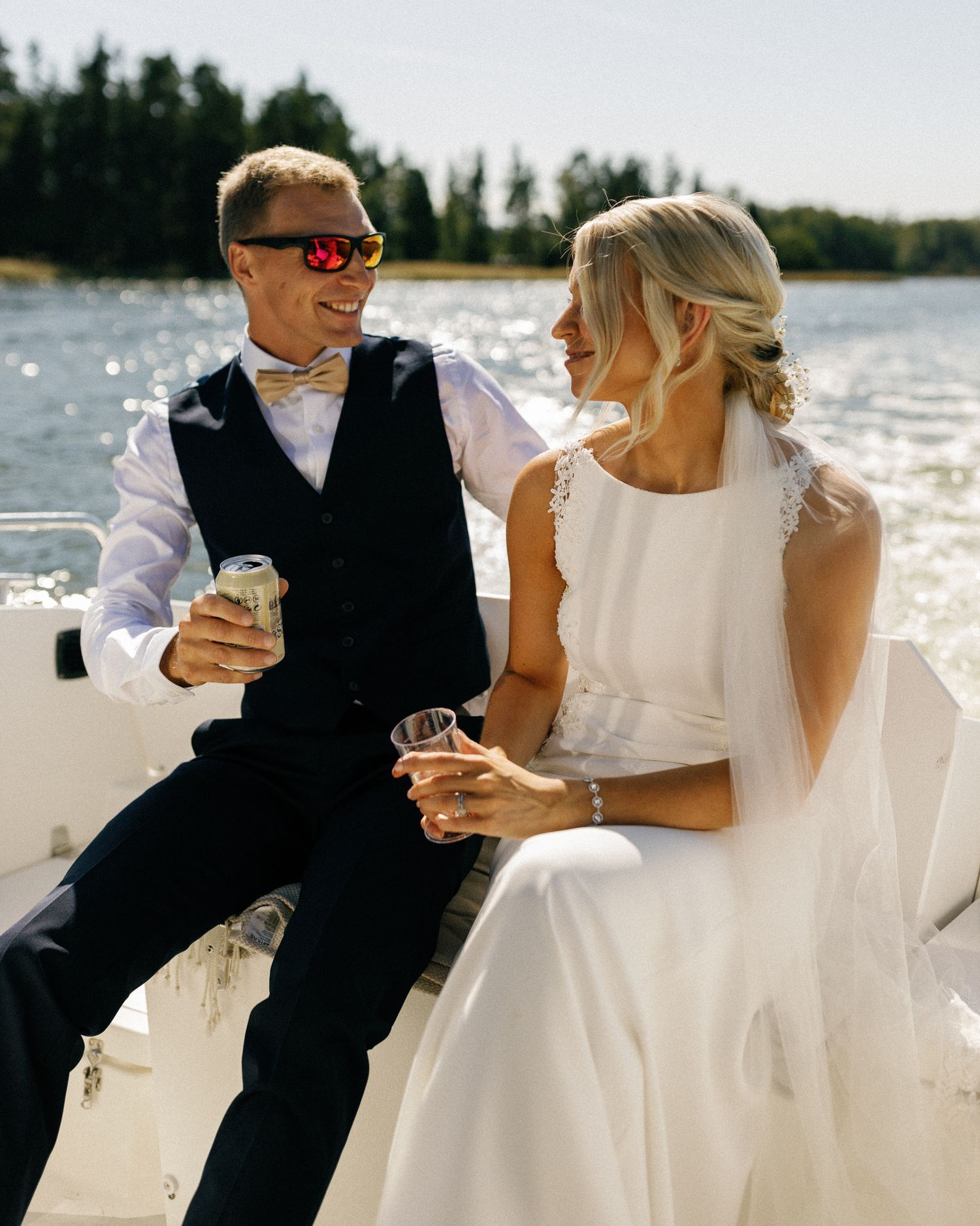 Wedding couple sits together on a boat deck during a sunny afternoon celebration.