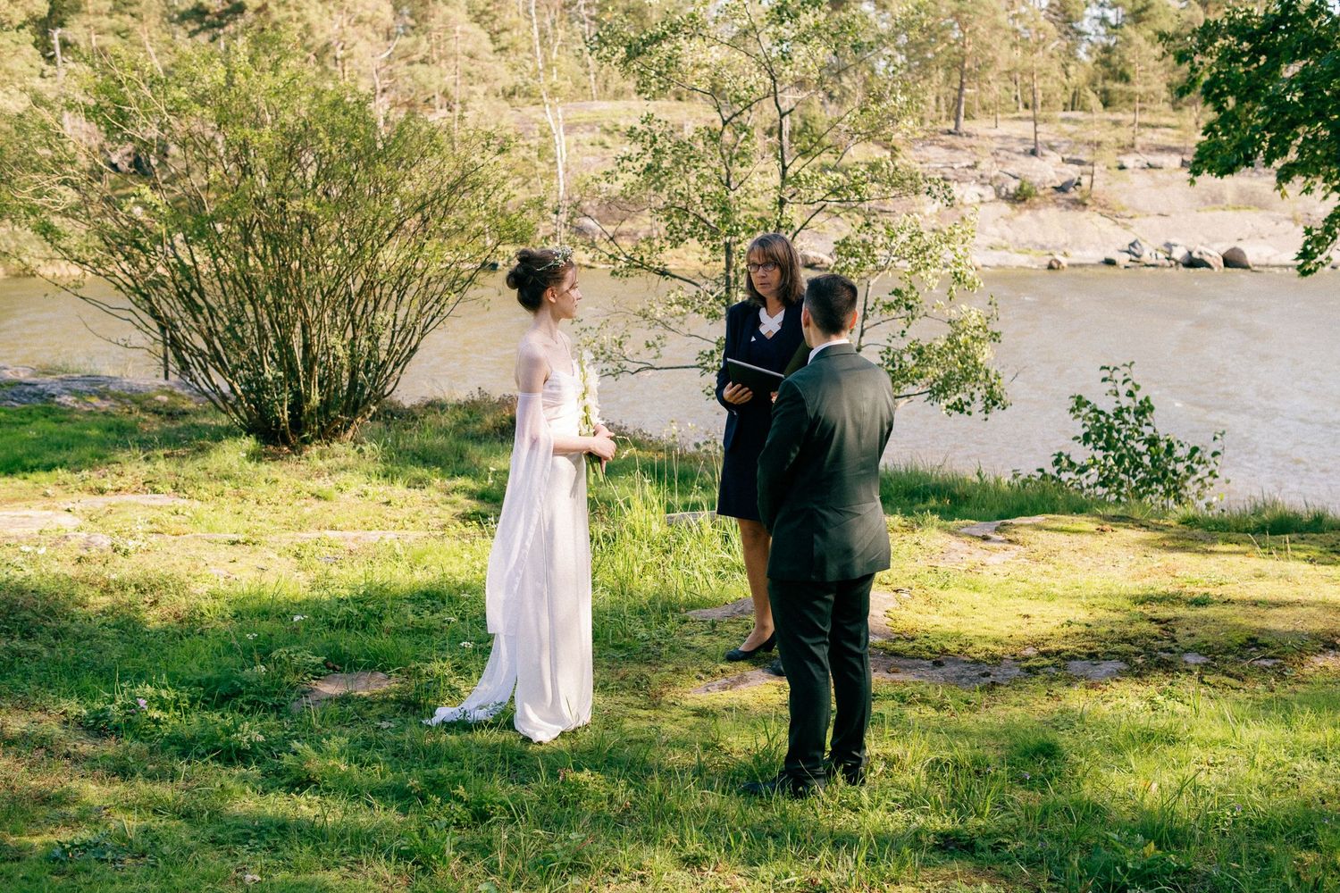 Guests mingle on a green lawn during an outdoor wedding with a historic yellow house in view.