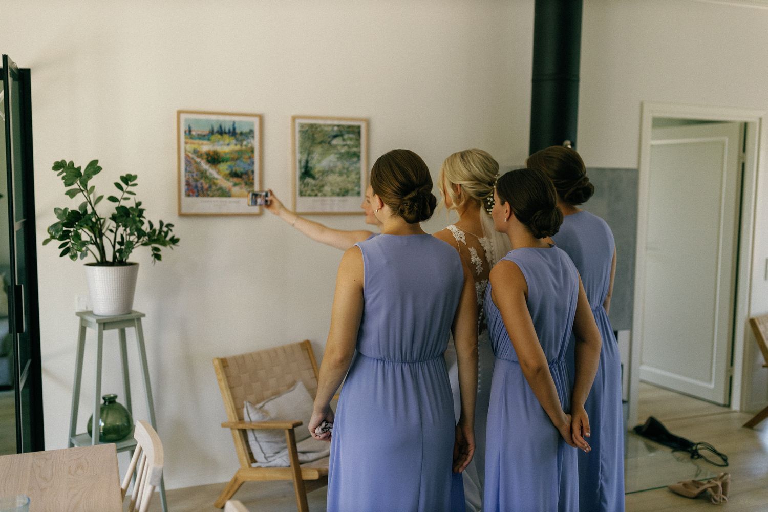 Bridesmaids in lavender dresses gathered together in a bright room.