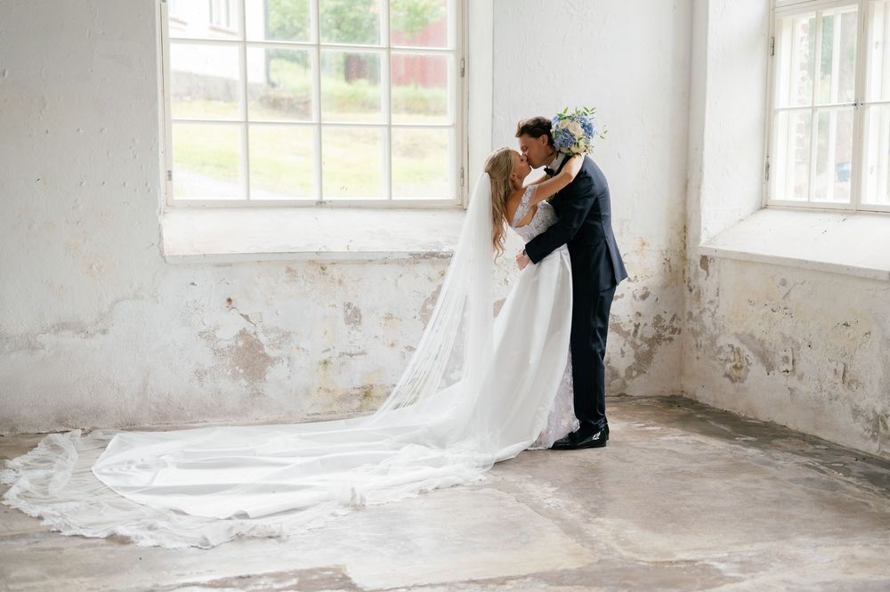 A wedding portrait showing the couple's kiss with the bride's cathedral veil flowing across the floor.