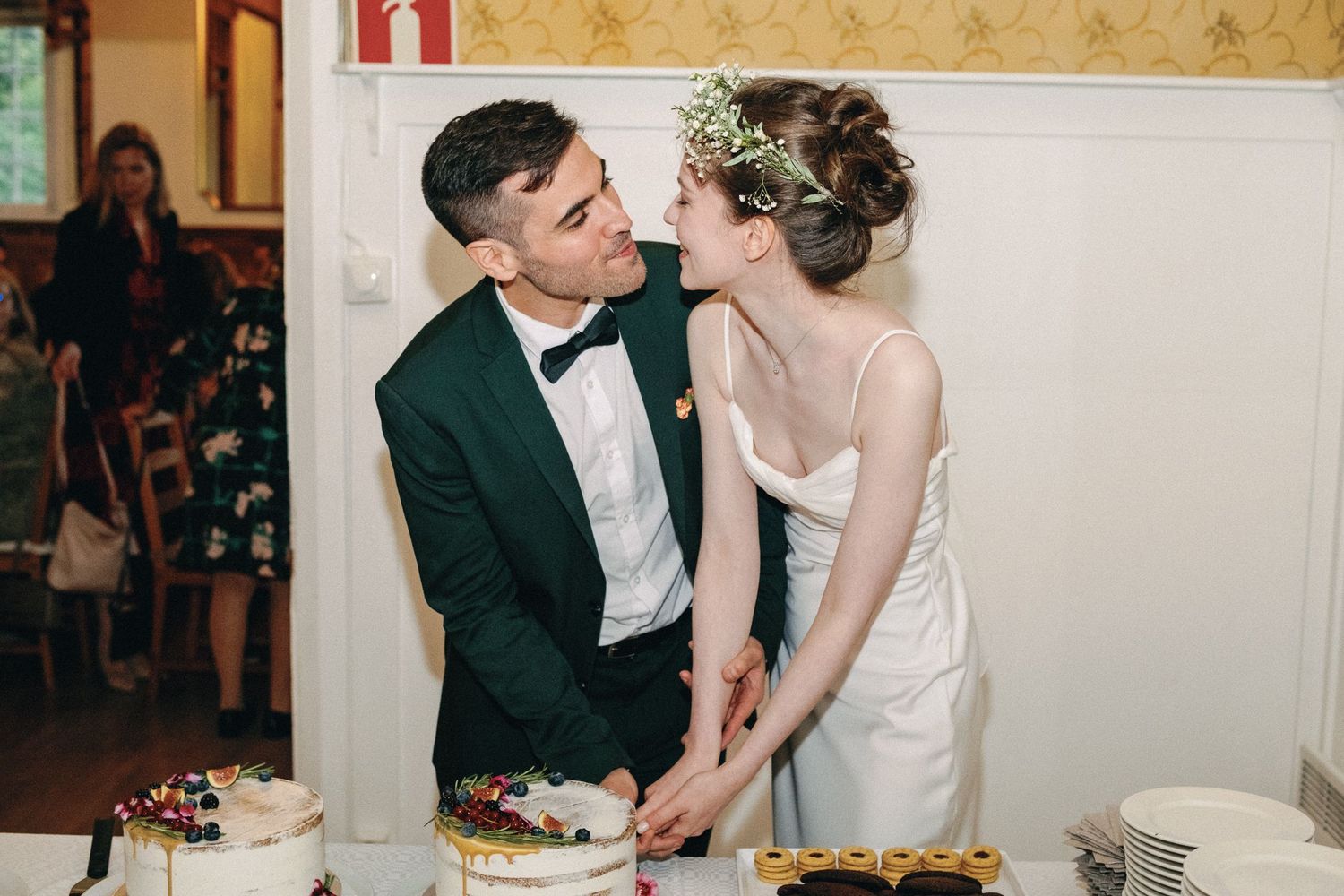 Newlyweds sharing a sweet moment while cutting their wedding cake at the reception.