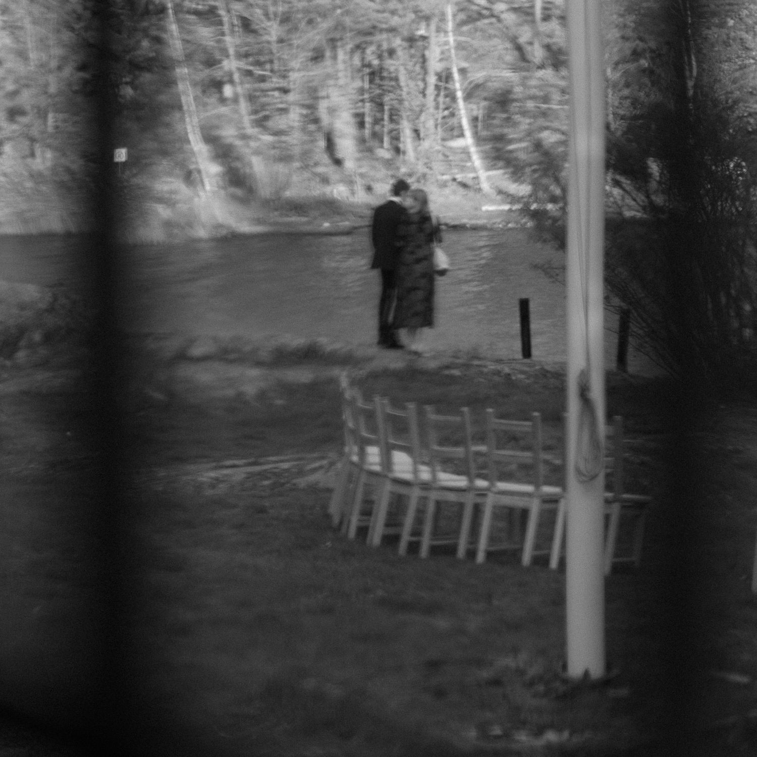 Black and white photograph of outdoor chairs arranged for a ceremony with trees in background.
