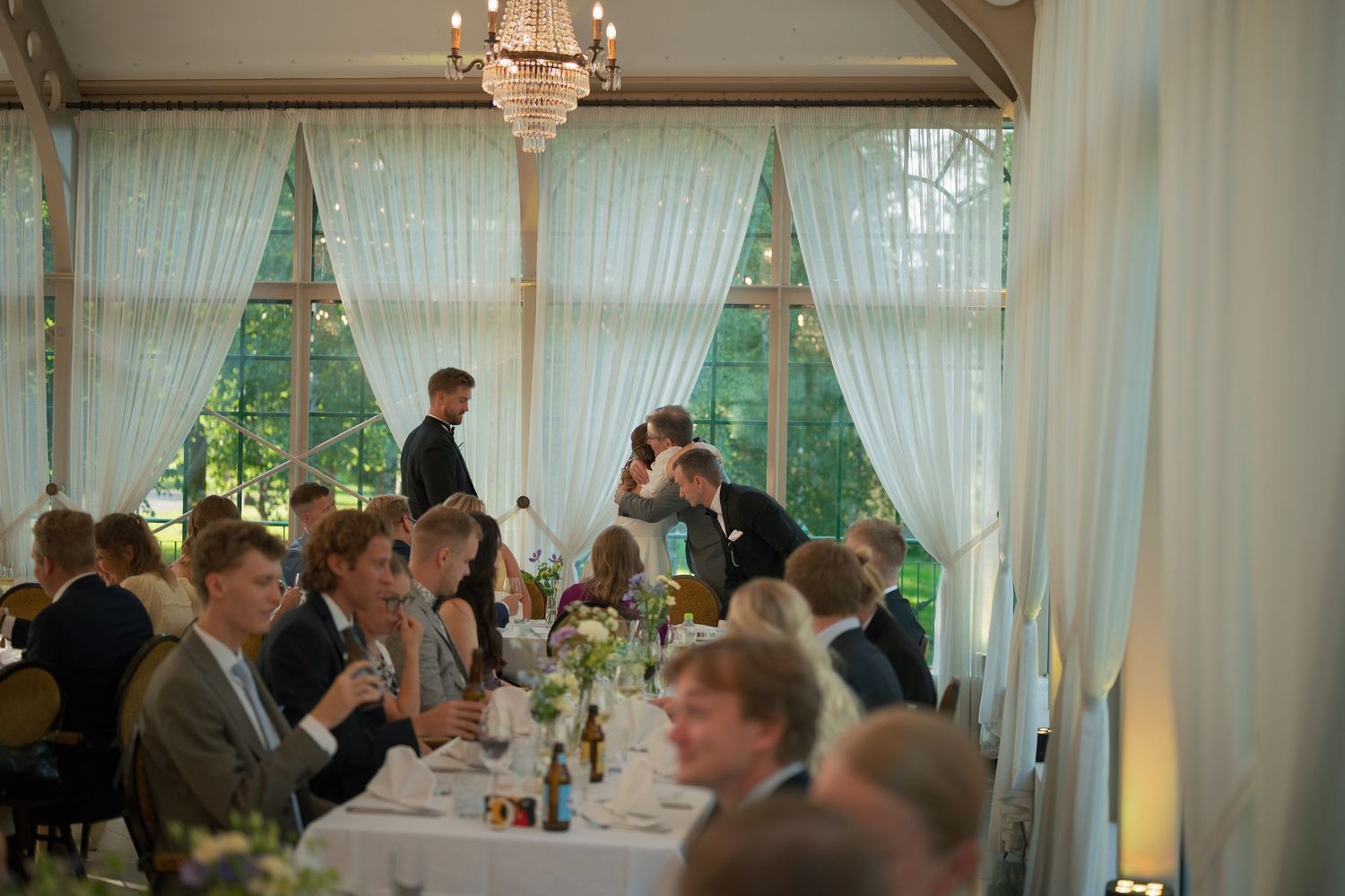 Wedding reception venue decorated with white curtains and elegant lighting.