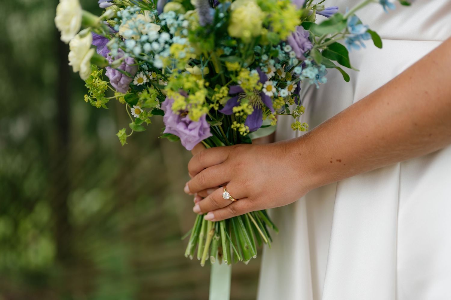 Close-up of wedding bouquet featuring blue, purple, and green flowers.