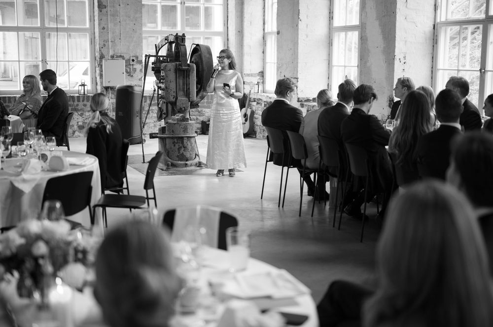Wedding reception guests gathered in a bright, airy industrial venue.