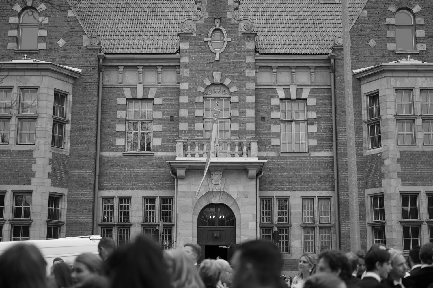 Historic brick building facade with crowd gathered in front during what appears to be a protest or demonstration.