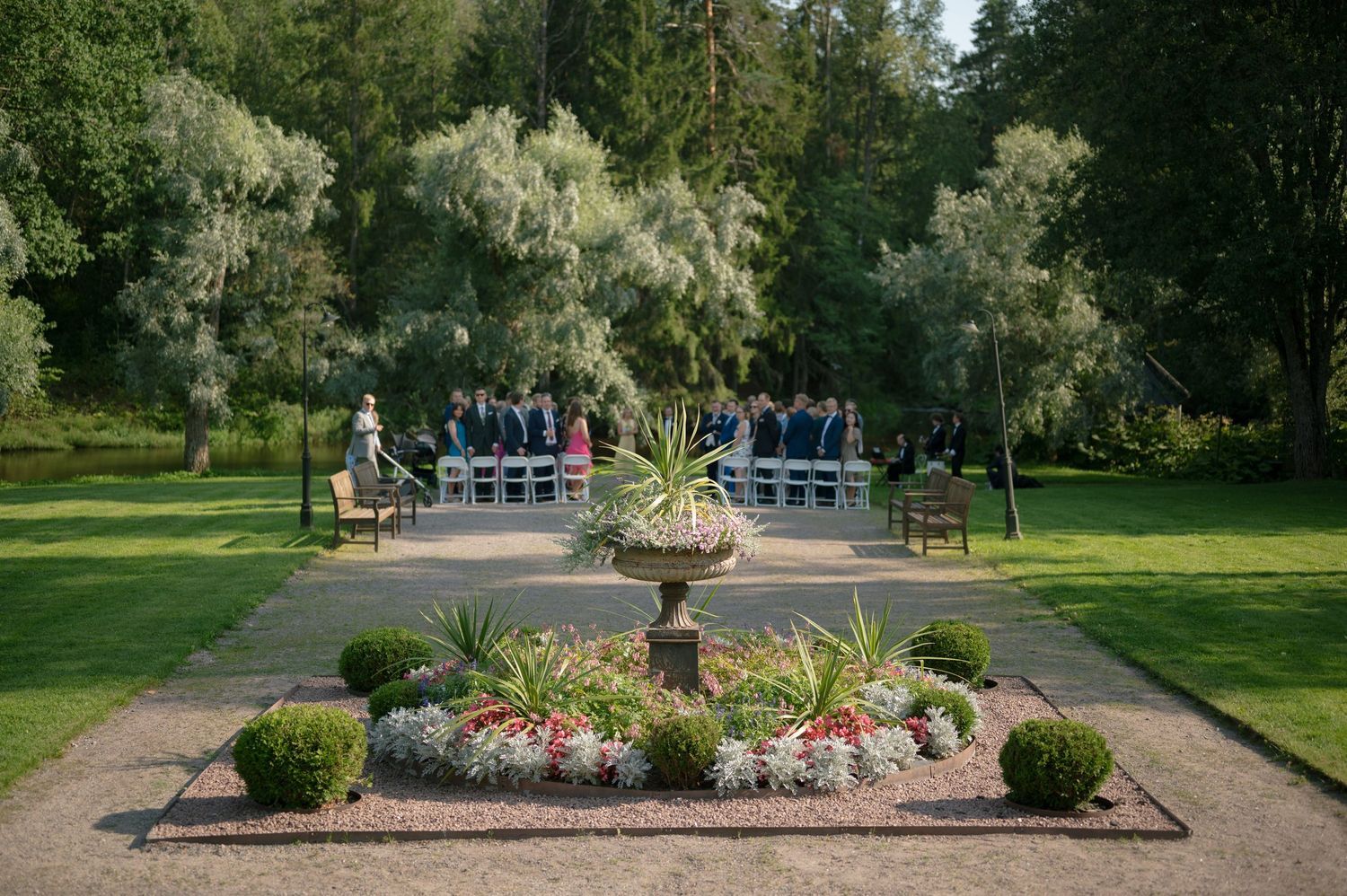 Panoramic view of a formal garden path with manicured landscaping and trees at an elegant venue.