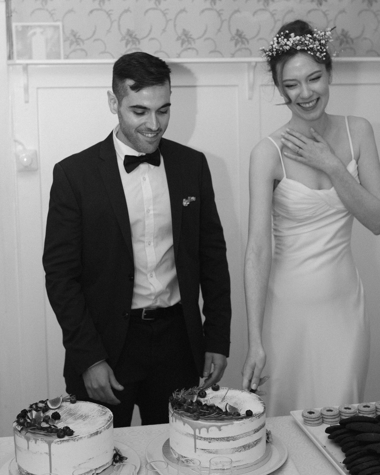 Couple sharing joyful moments while cutting multiple wedding cakes at their reception.