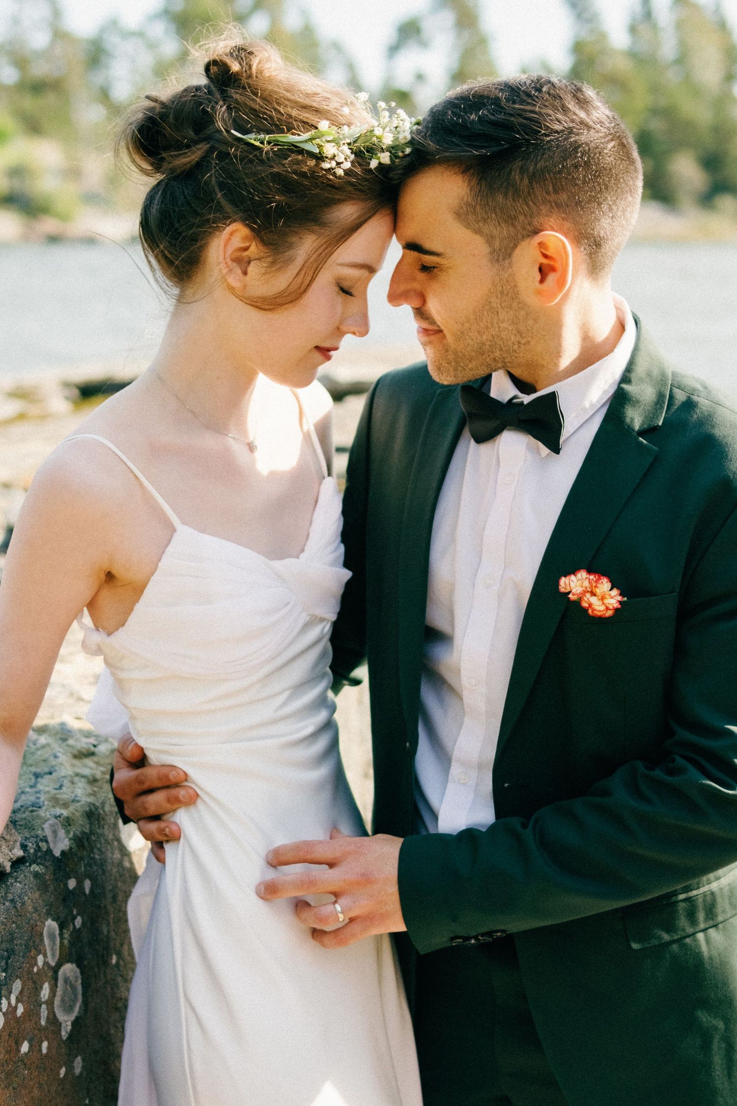 A romantic wedding photoshoot with a couple in formal attire against a sunlit outdoor backdrop.