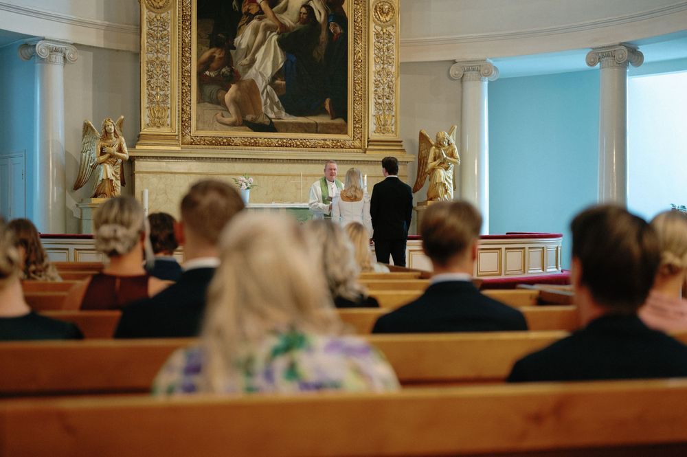 Elegant church interior with ornate gold details and wooden pews during a wedding ceremony.