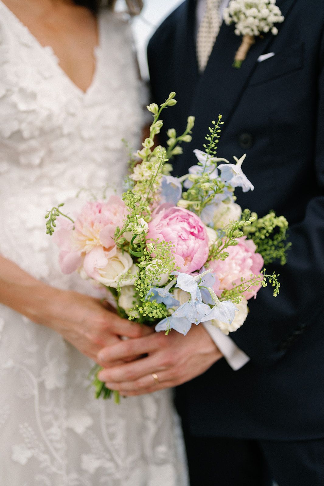 Close-up details of delicate pink and white wedding bouquet with greenery accents.