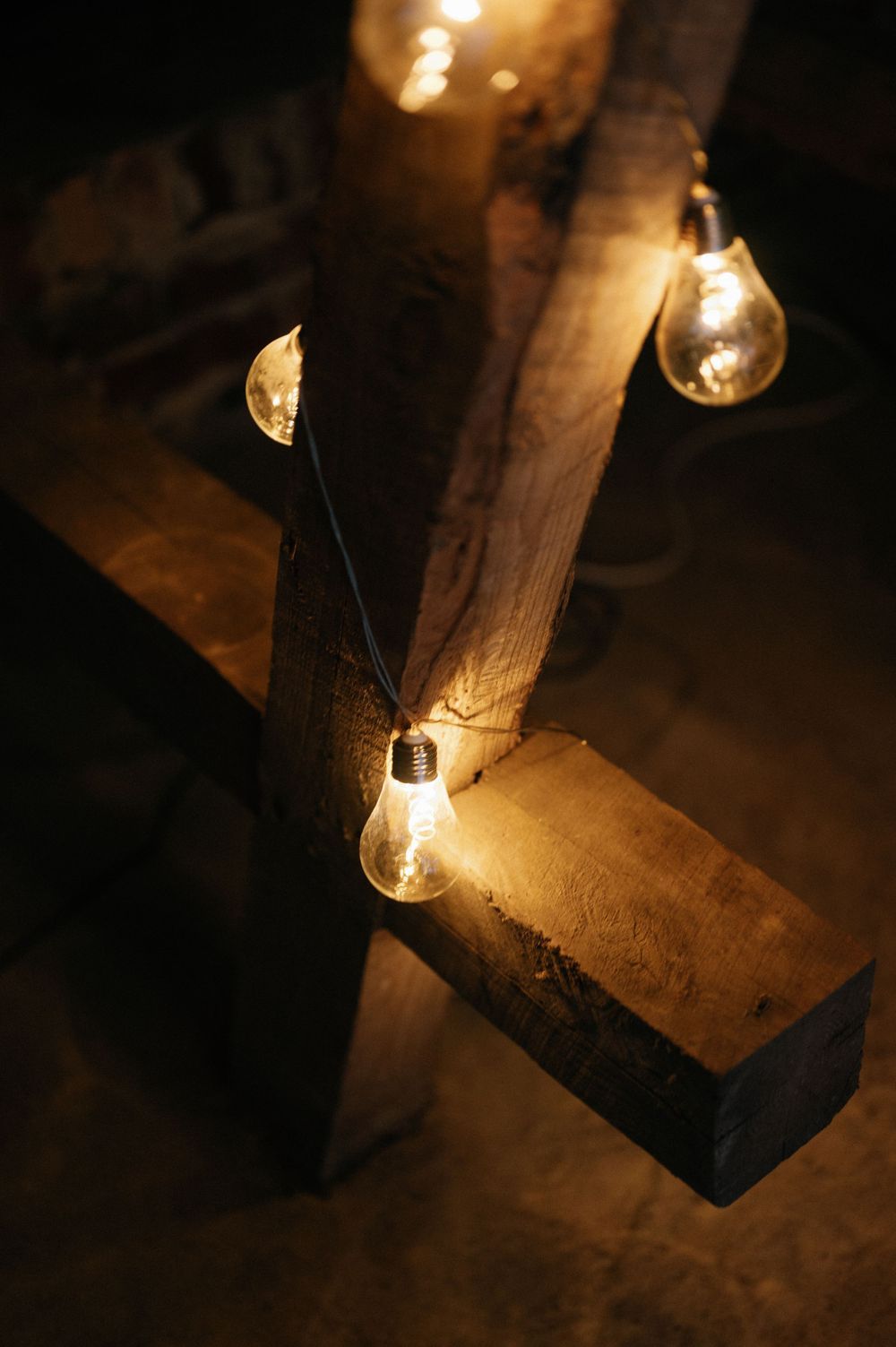 Rustic wooden beams with glowing Edison bulbs creating warm ambient lighting.