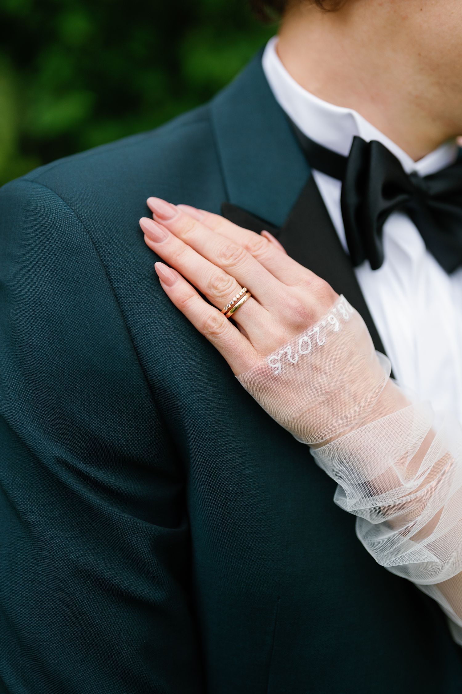Close-up of a bride's hand wearing a delicate white lace glove and wedding ring.