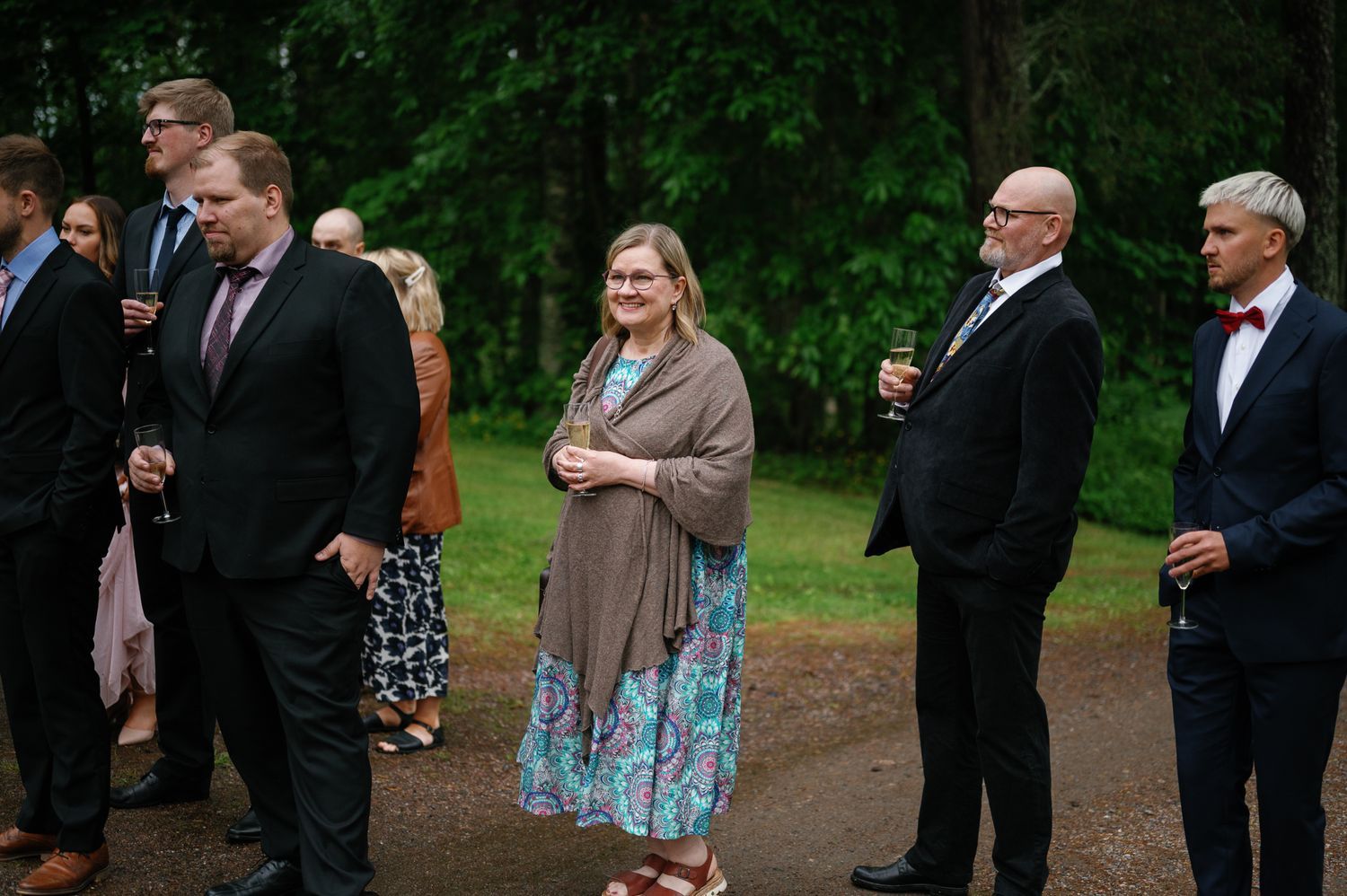 Wedding guests mingling outside in formal wear during an outdoor reception.