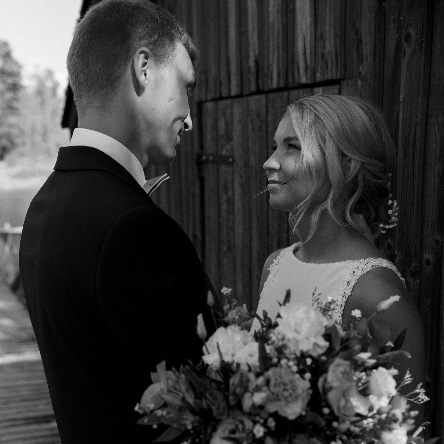 Dramatic black and white wedding portraits against a rustic wooden backdrop.
