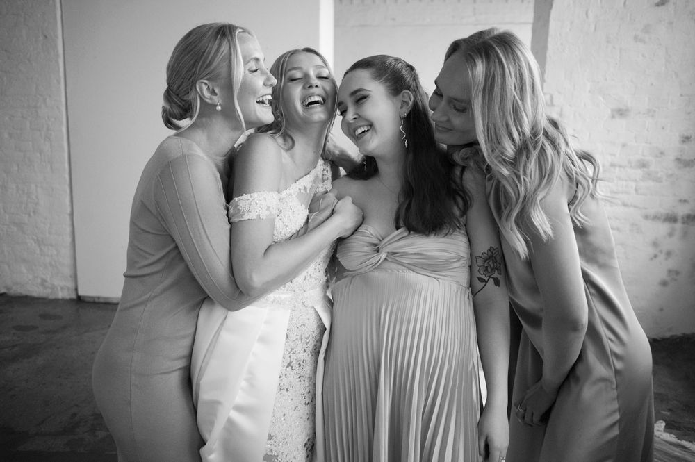 Black and white photo capturing joyful laughter during a wedding celebration.