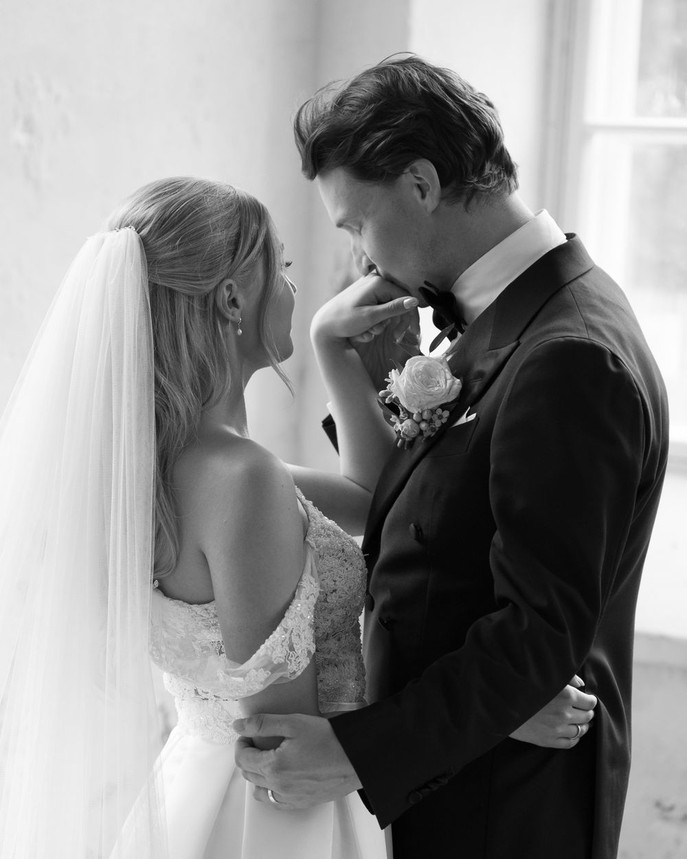A romantic wedding portrait showing tender interaction between bride and groom in classic formal attire.