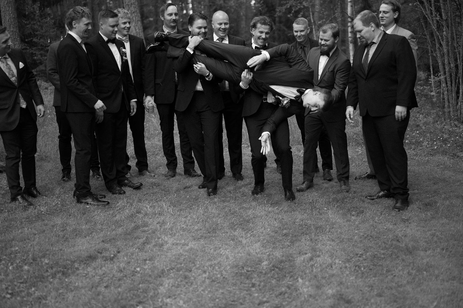 Large group photo of wedding party members in formal attire standing outdoors.