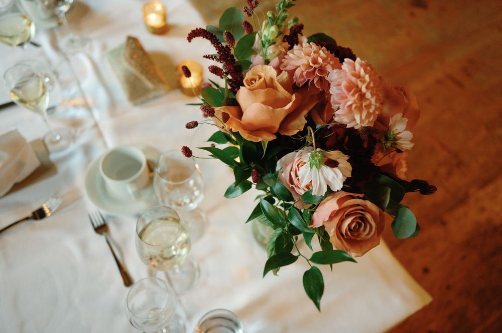 A romantic table setting with pink and peach floral centerpiece and wine glasses.