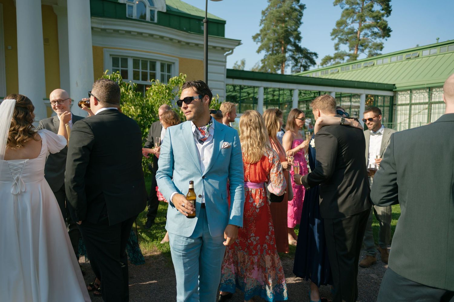 Wedding guests mingling outdoors at an elegant summer garden party.