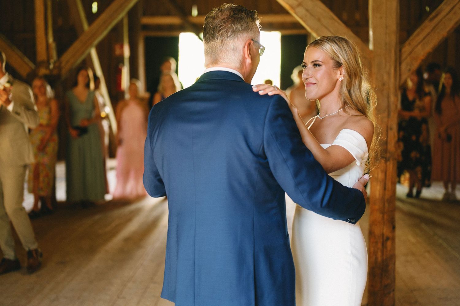 A couple shares an intimate slow dance in a wooden barn setting at their wedding reception.