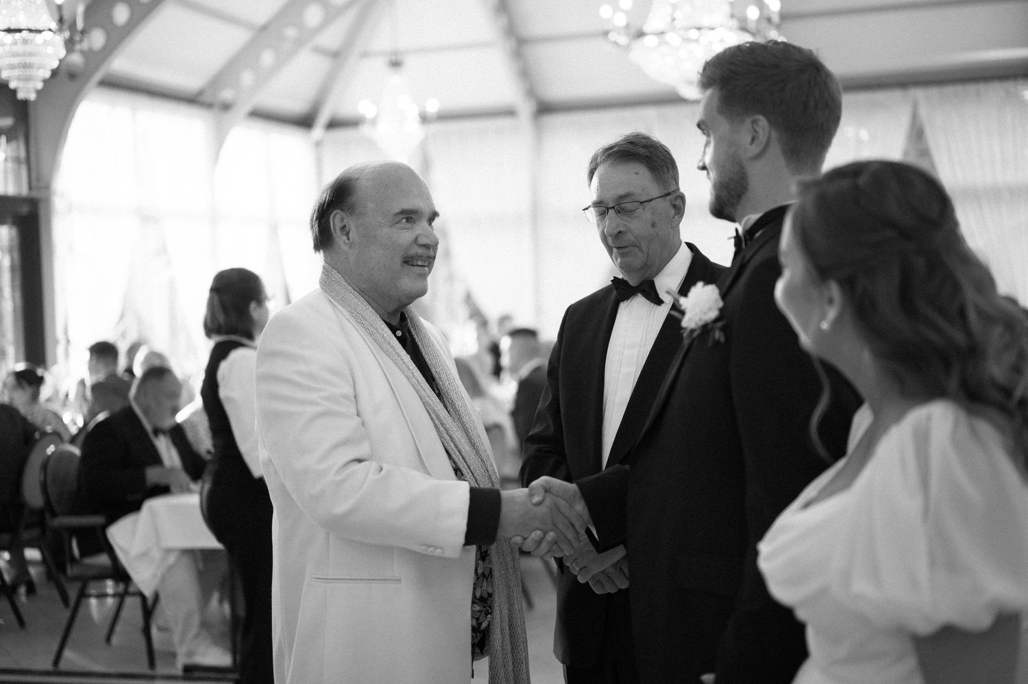 Black and white photo showing guests mingling and socializing at an elegant wedding reception.