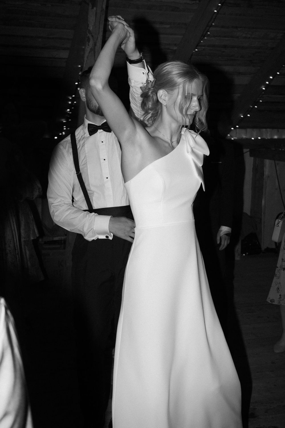 Couples slow dancing in formal attire at a dimly lit wedding reception.