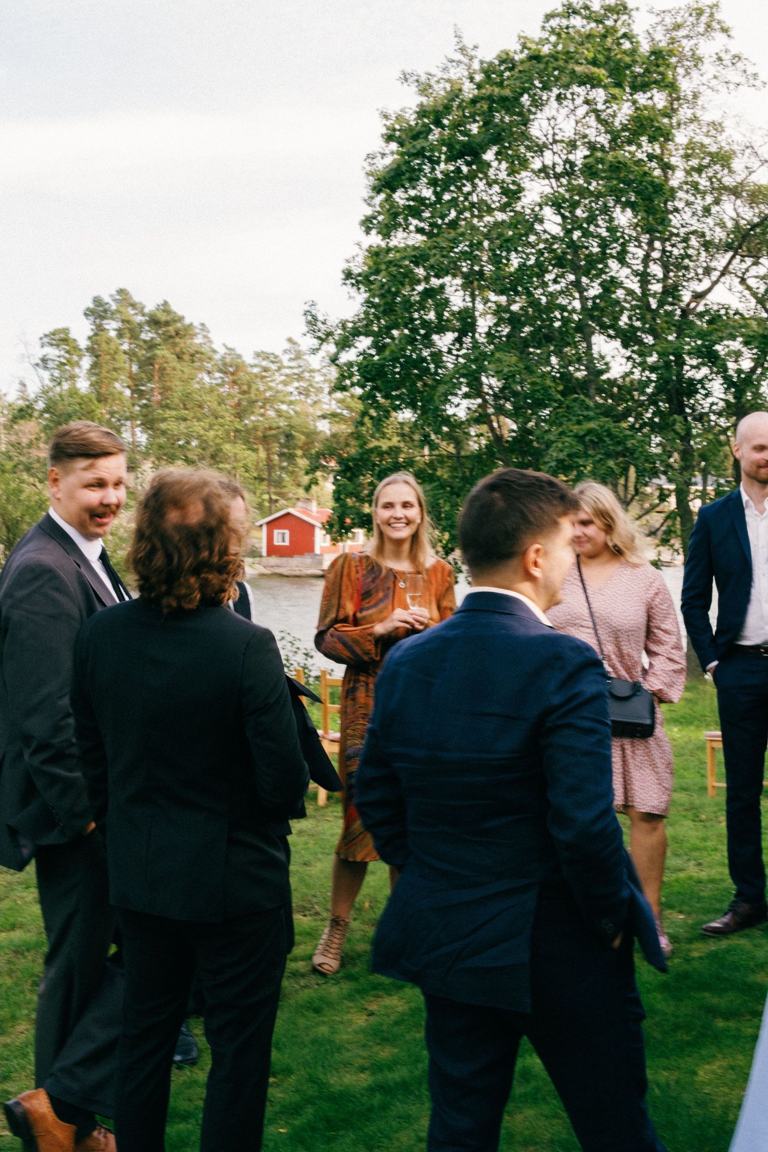 Guests gathered on a green lawn with a red barn visible in the background during an outdoor event.