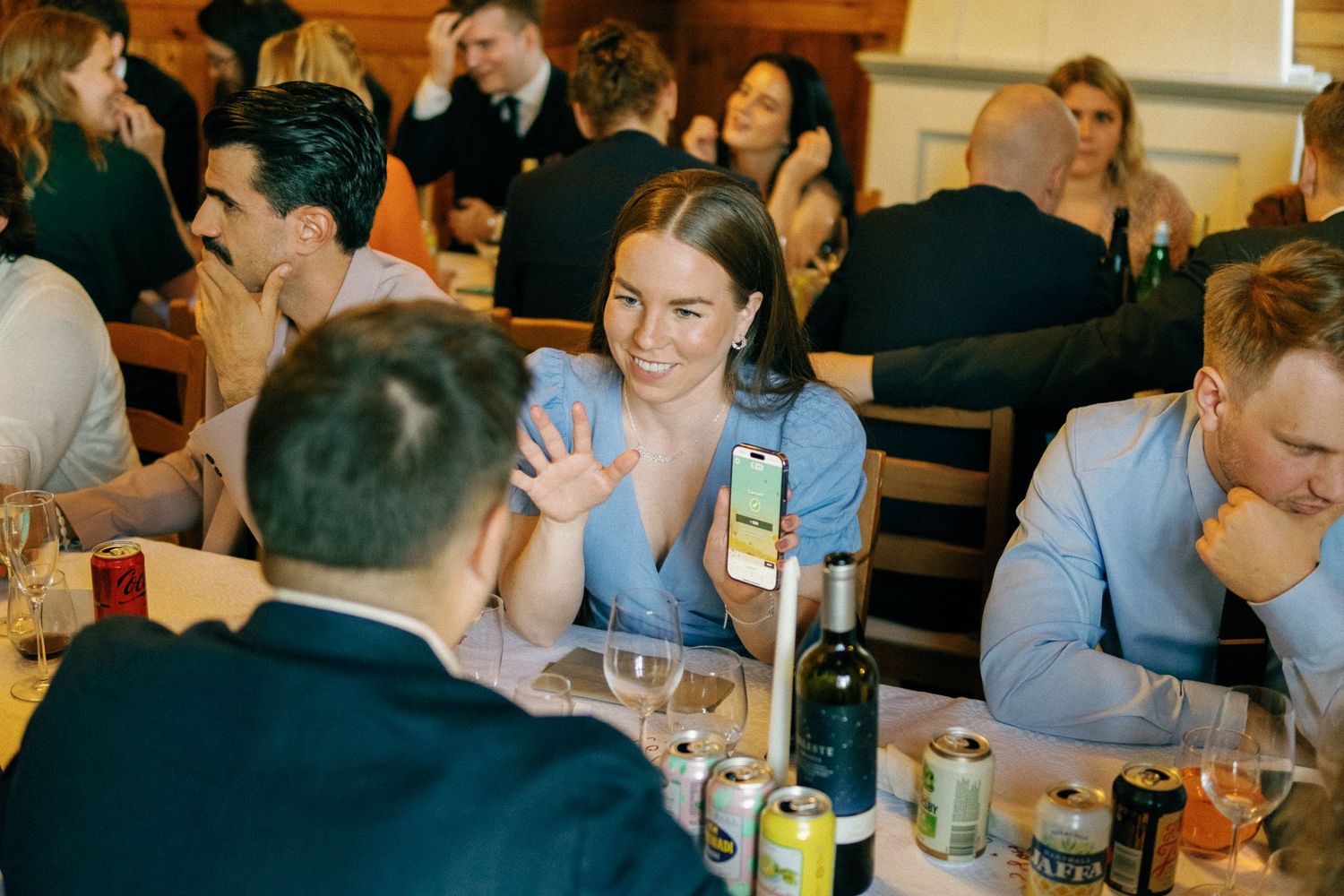 Guests engaged in lively conversation at a dinner reception with wine bottles and glasses on the table.