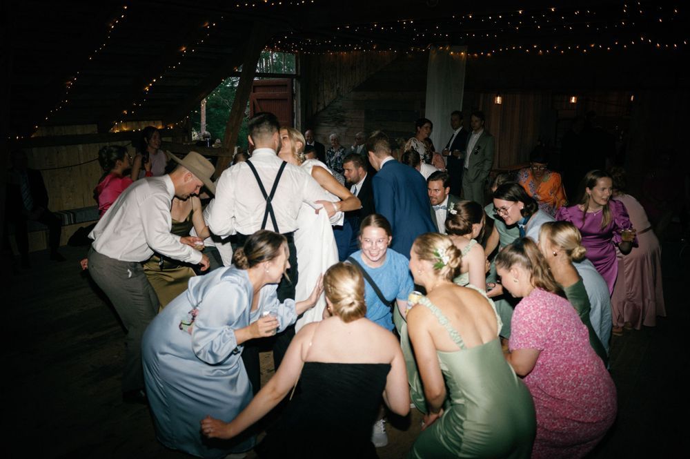 Wedding reception dance party with guests celebrating in a dark venue.