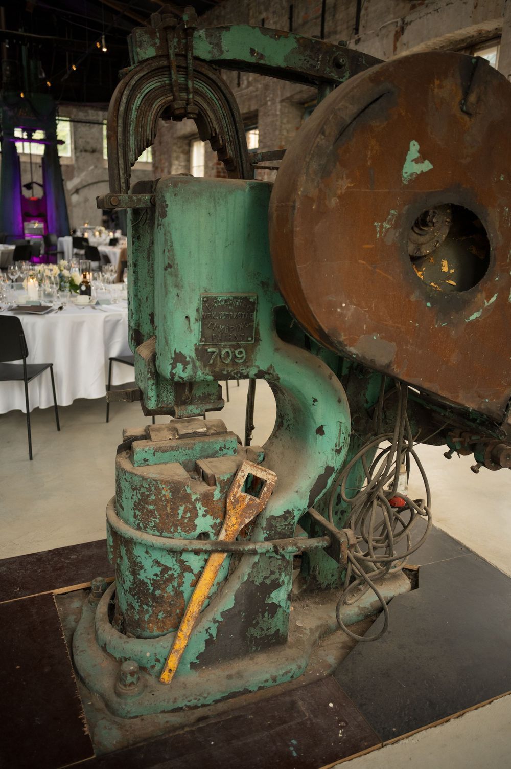 Old green industrial machinery displayed in a converted warehouse event space.