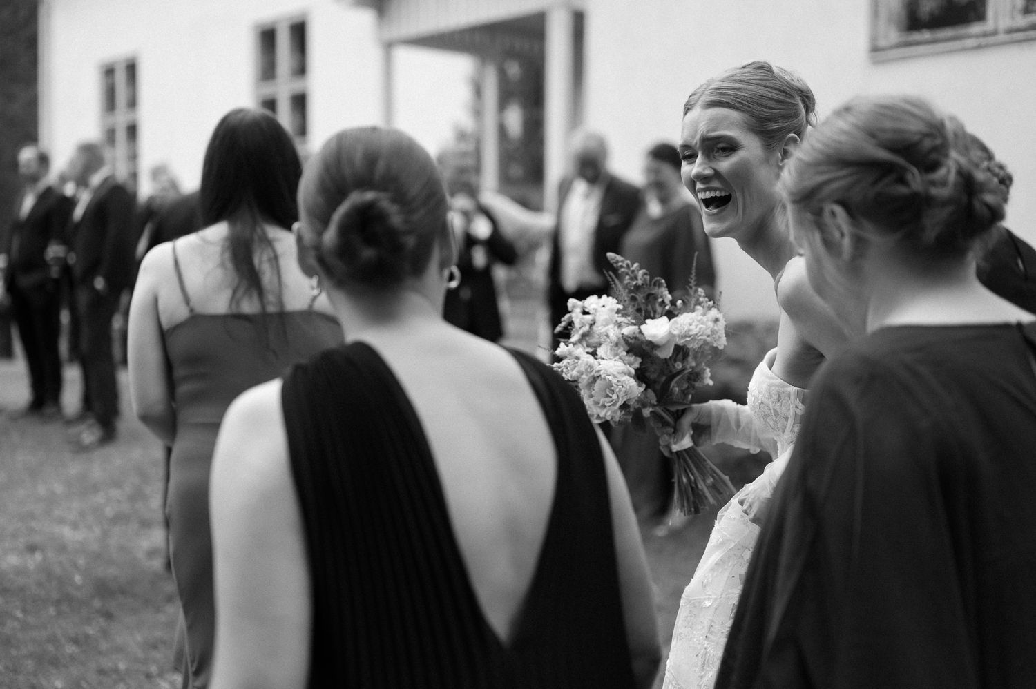 Black and white candid shots of wedding guests mingling and celebrating at the reception.