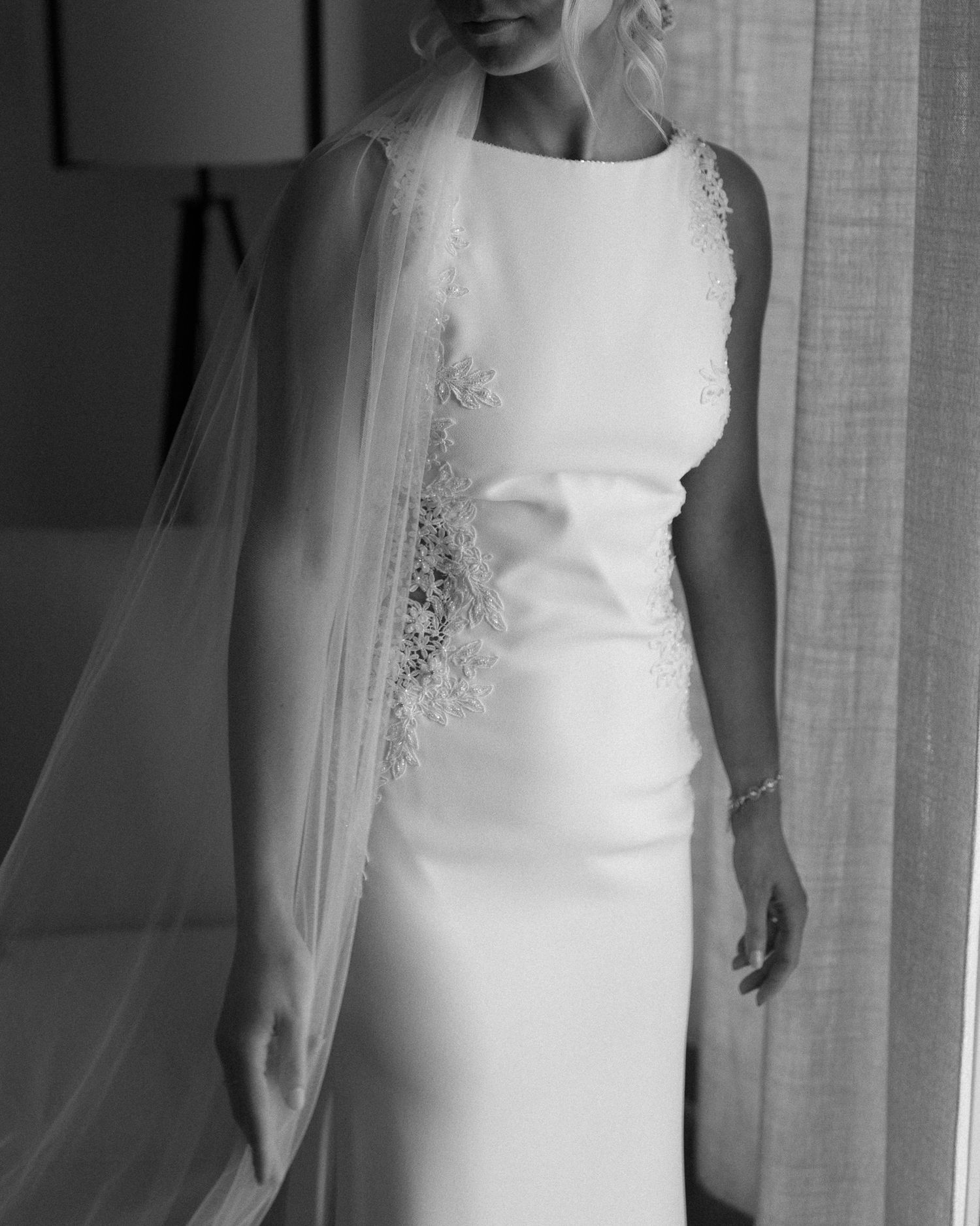 Close-up details of a sleek white wedding dress with delicate lace accents.