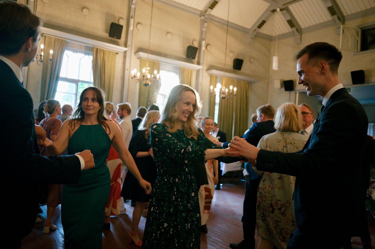 People mingling and socializing at an elegant indoor event with chandeliers and formal attire.