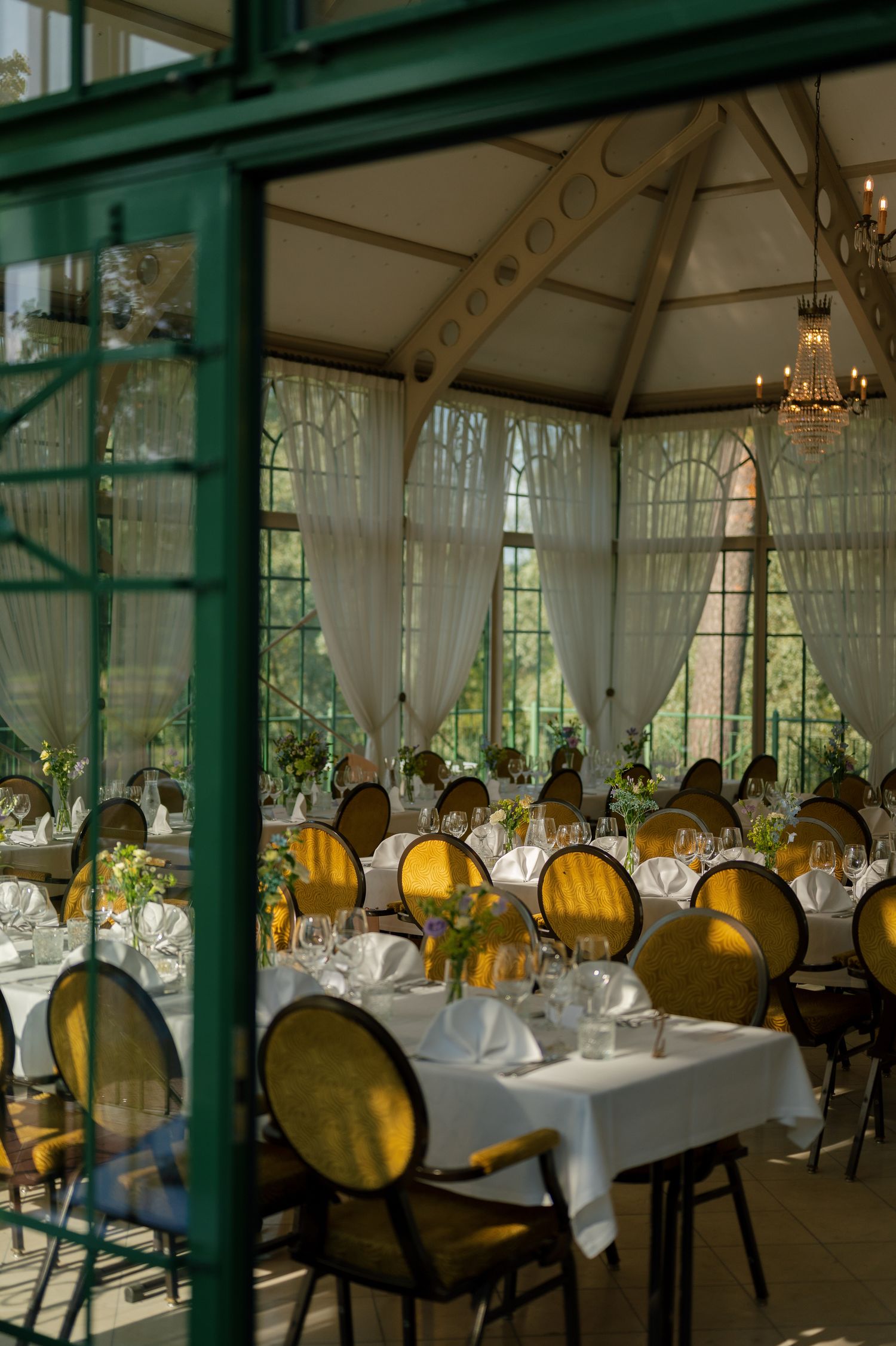 Elegant restaurant interior with white tablecloths, ornate chairs, and sheer curtains creating a romantic ambiance.