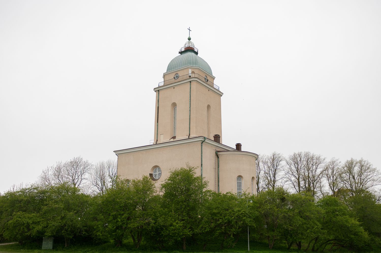 A tall grain elevator or silo building stands prominently against a cloudy sky with trees in the background.