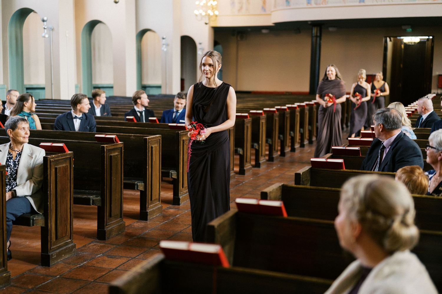 A group gathers in a formal ceremony space with dark wood paneling and decorative lighting.