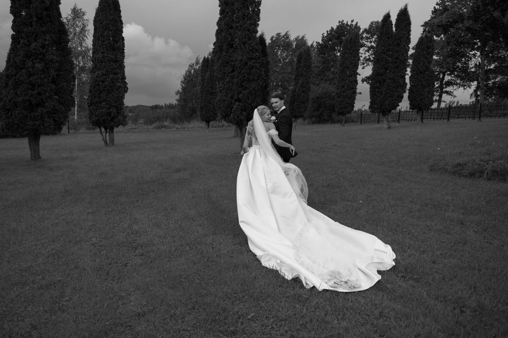 Wedding couple walking together through a scenic garden with tall cypress trees.