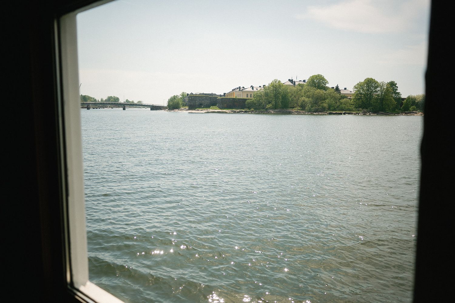 Panoramic view of a calm lake with sailboats and shoreline visible in the distance.
