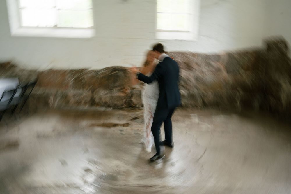 Blurred motion of dancers spinning in an empty industrial room with white walls.