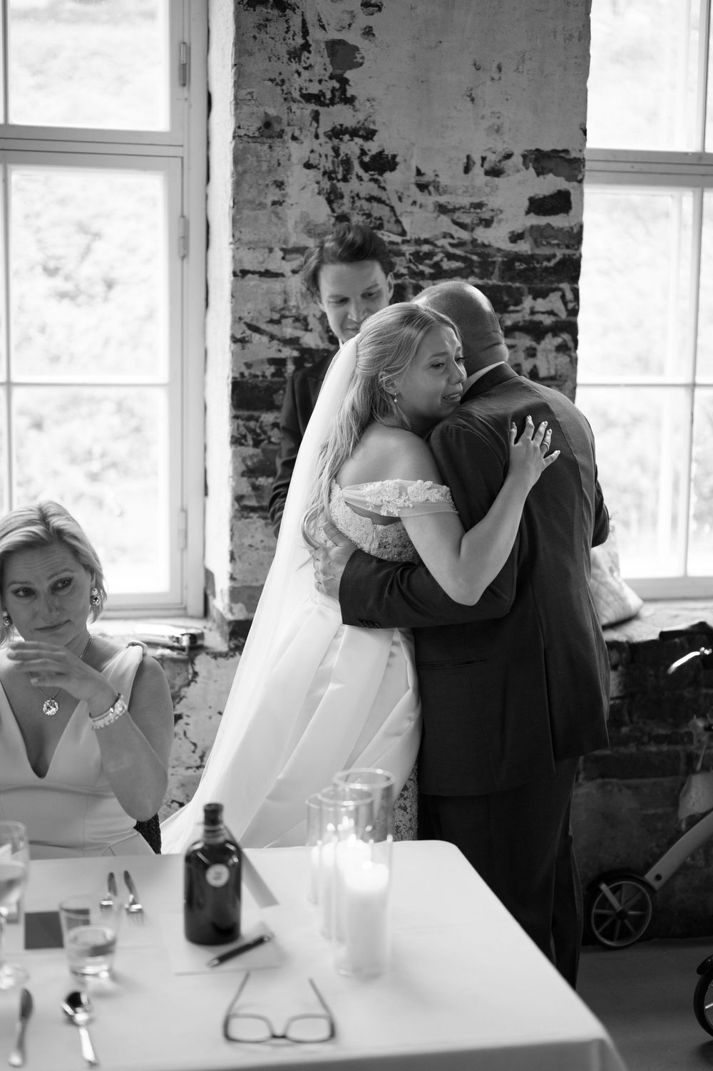 Emotional moments captured during wedding reception in rustic brick venue.